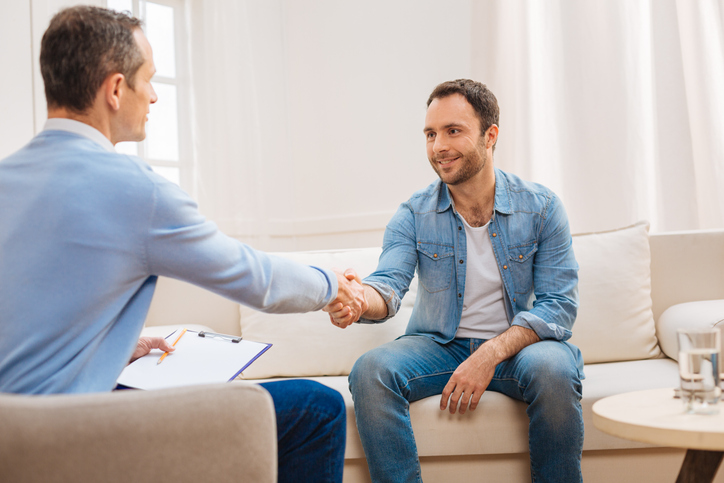 Happy glad man shaking hands with psychologist